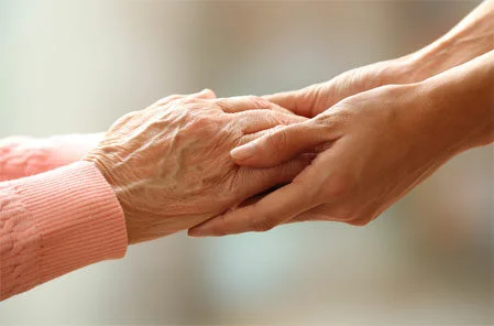 carer holding hands with elderly landy